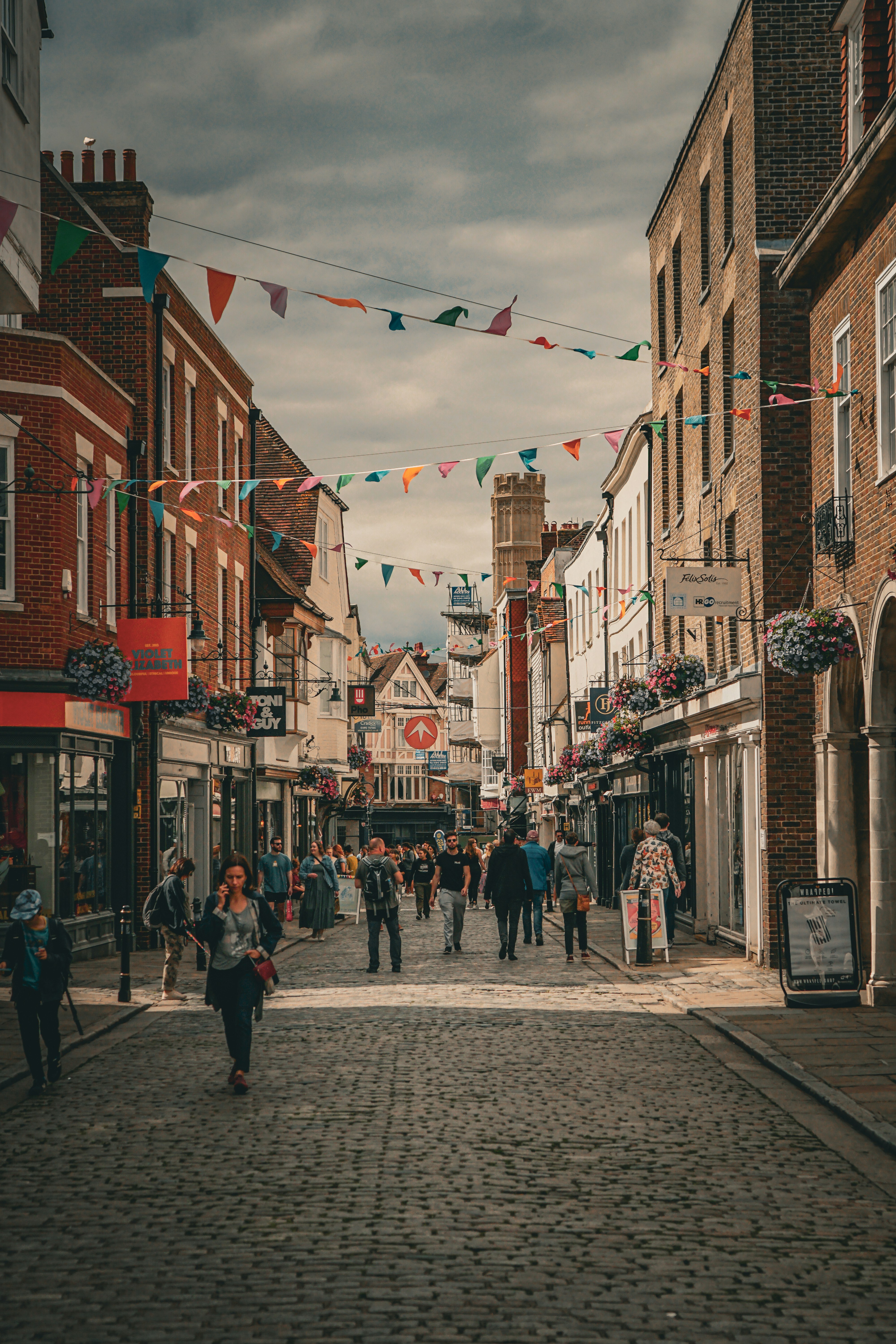 Vibrant high street scene showing thriving independent shops, cafes, and busy shoppers. Bright, colorful, optimistic feel.